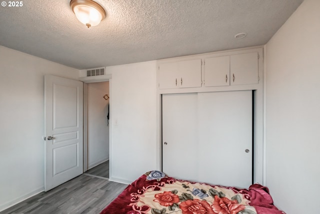 bedroom featuring wood-type flooring, a closet, and a textured ceiling