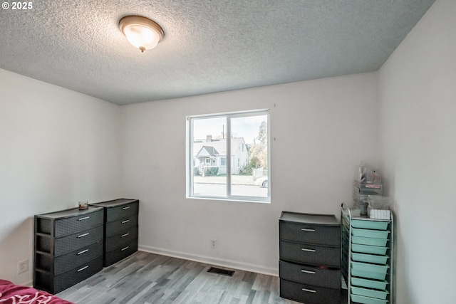 bedroom featuring light hardwood / wood-style floors and a textured ceiling