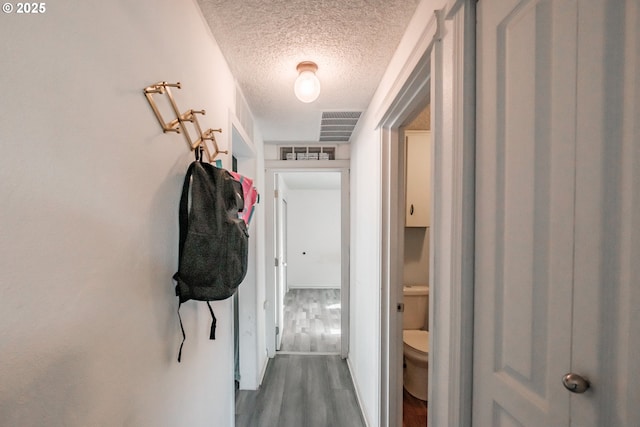 hall with hardwood / wood-style floors and a textured ceiling