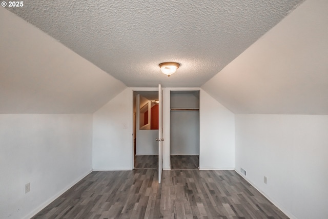 bonus room featuring vaulted ceiling, a textured ceiling, and dark hardwood / wood-style flooring