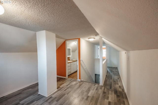 bonus room featuring dark hardwood / wood-style flooring, vaulted ceiling, and a textured ceiling