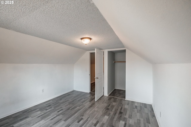 bonus room with lofted ceiling, dark wood-type flooring, and a textured ceiling