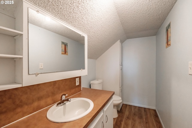 bathroom with lofted ceiling, vanity, wood-type flooring, a textured ceiling, and toilet