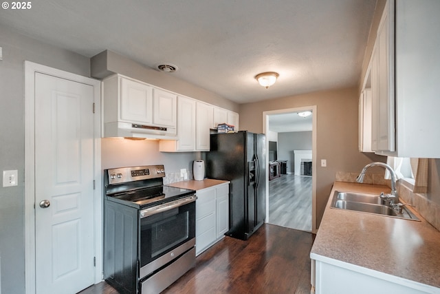 kitchen featuring sink, dark wood-type flooring, white cabinets, black fridge, and stainless steel electric stove