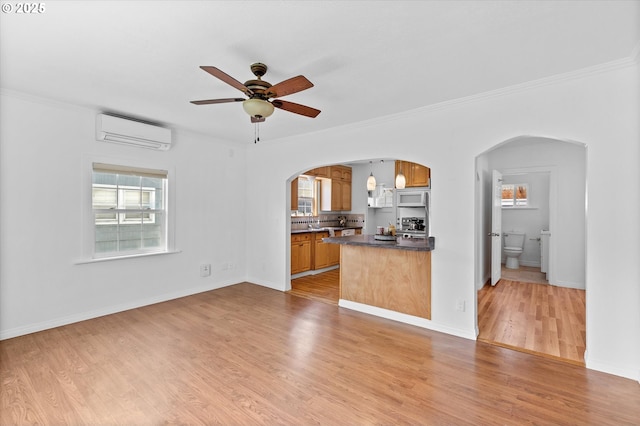 521 21st Ave, Longview, WA 98632 - unfurnished living room with an AC wall unit, arched walkways, ceiling fan, ornamental molding, and light wood-style flooring