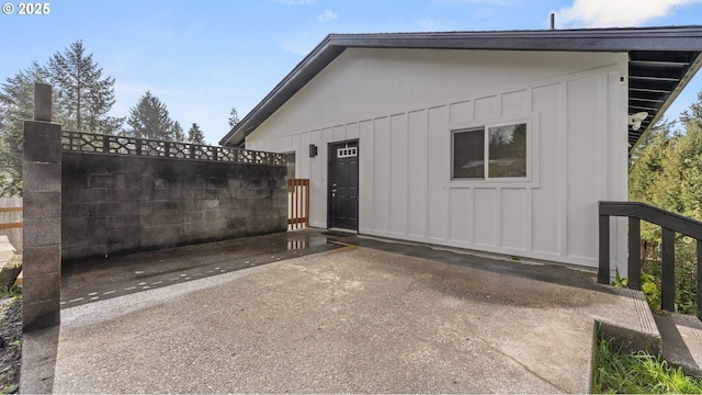 exterior space featuring a patio area, fence, and board and batten siding