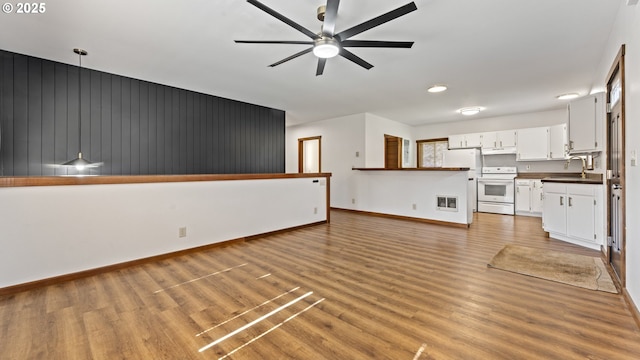 unfurnished living room with light wood-style floors, a ceiling fan, baseboards, and a sink