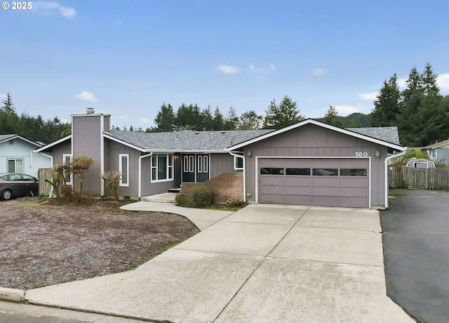 view of front facade with driveway, fence, an attached garage, a shingled roof, and a chimney