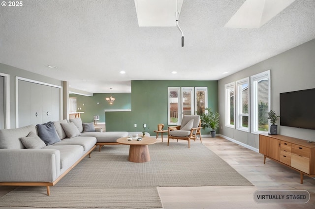 living area featuring recessed lighting, light wood-style floors, baseboards, and a textured ceiling