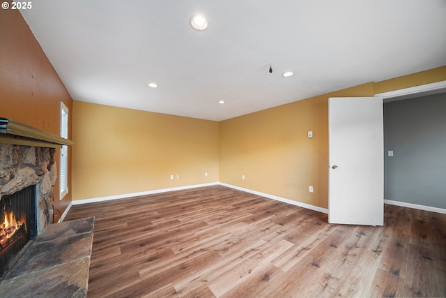unfurnished living room featuring wood finished floors, a fireplace, and baseboards