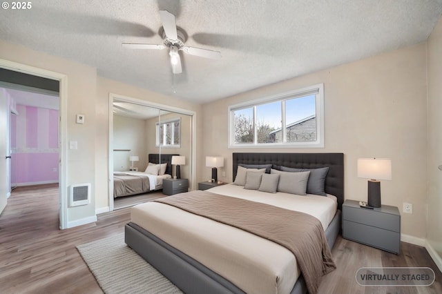 bedroom with ceiling fan, baseboards, wood finished floors, a closet, and a textured ceiling