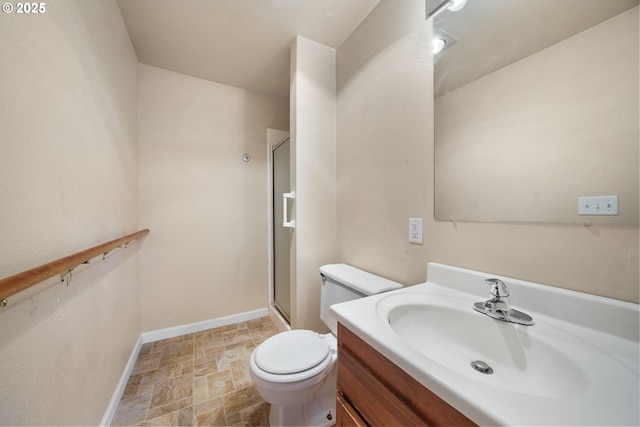bathroom with a shower stall, baseboards, toilet, stone finish floor, and vanity
