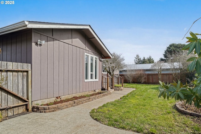 view of side of property featuring a lawn and fence