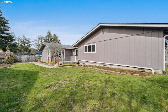exterior space featuring a deck, a lawn, fence, and crawl space