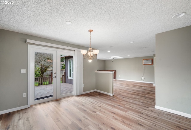 unfurnished dining area featuring wood finished floors, baseboards, french doors, and a textured ceiling