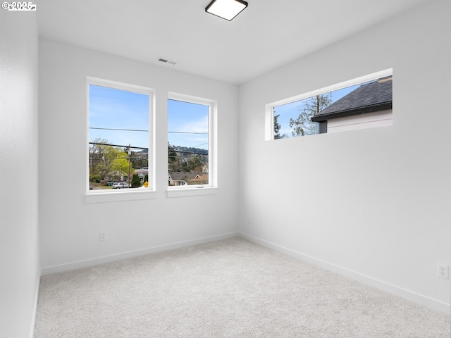 carpeted empty room featuring visible vents and baseboards
