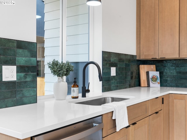 kitchen featuring stainless steel dishwasher, light countertops, a sink, and decorative backsplash
