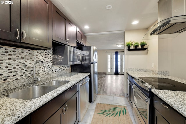 kitchen featuring a sink, tasteful backsplash, dark brown cabinetry, appliances with stainless steel finishes, and wall chimney range hood