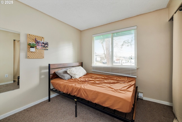 bedroom with a textured ceiling, baseboards, and carpet floors