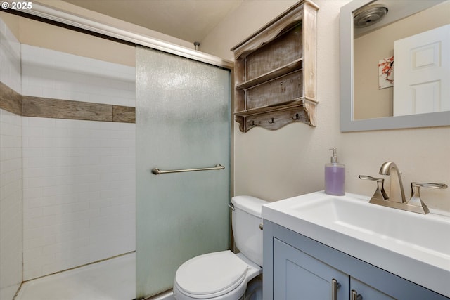 bathroom featuring vanity, a shower stall, and toilet