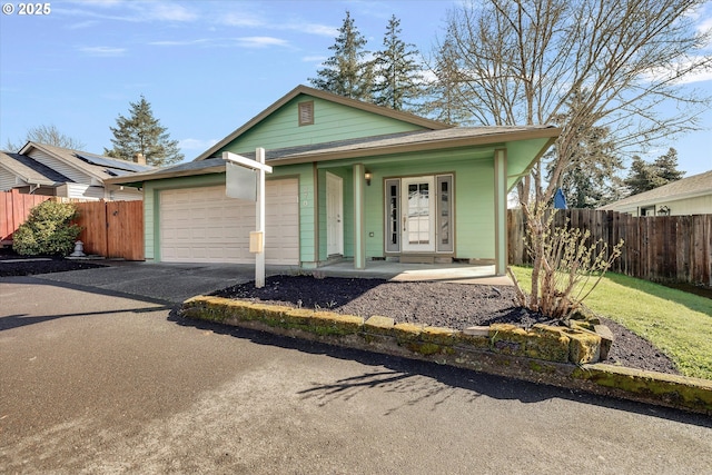 view of front of house featuring a garage, covered porch, driveway, and fence