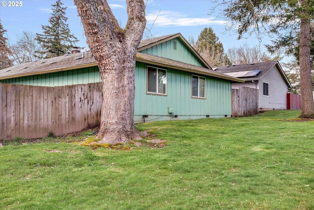 rear view of house with a lawn, fence, a shingled roof, crawl space, and a chimney