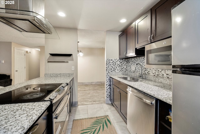 kitchen featuring dark brown cabinets, decorative backsplash, exhaust hood, stainless steel appliances, and a sink