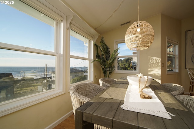 dining room featuring a chandelier, hardwood / wood-style floors, and a water view