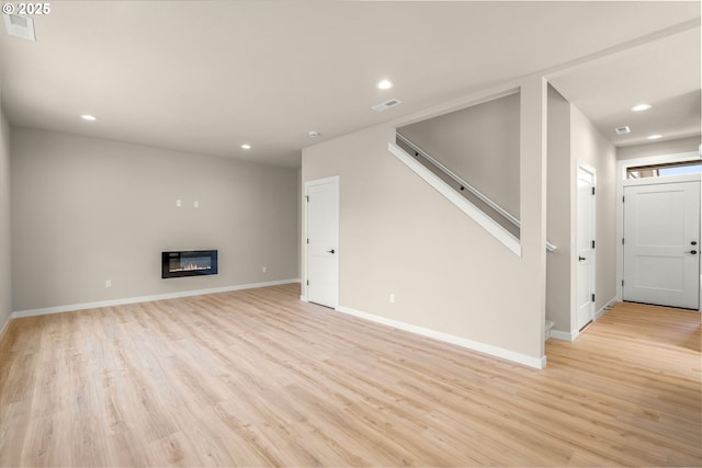 1405 Gordon Ct, The Dalles, OR 97058 - unfurnished living room with light wood finished floors, recessed lighting, a glass covered fireplace, and stairway