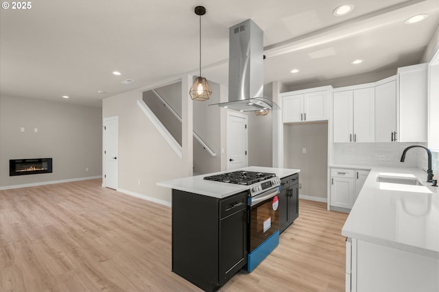 1405 Gordon Ct, The Dalles, OR 97058 - kitchen featuring island range hood, stainless steel gas range, dark cabinets, light wood-style flooring, and light countertops