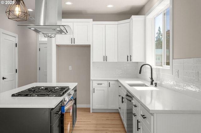 1405 Gordon Ct, The Dalles, OR 97058 - kitchen featuring island range hood, appliances with stainless steel finishes, light wood-style floors, light countertops, and decorative backsplash