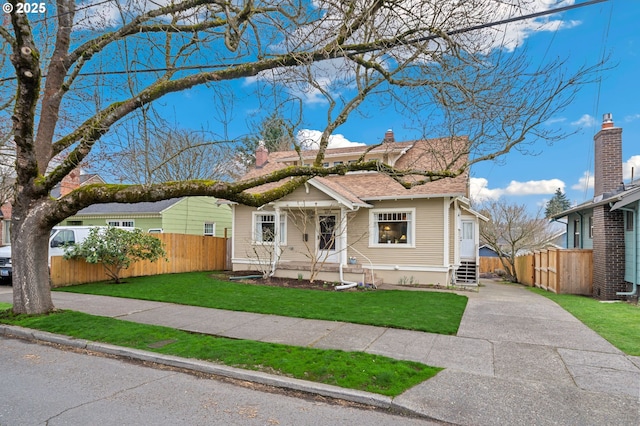 bungalow-style house featuring entry steps, concrete driveway, a front yard, and fence