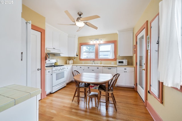 kitchen featuring under cabinet range hood, white appliances, white cabinetry, and a sink