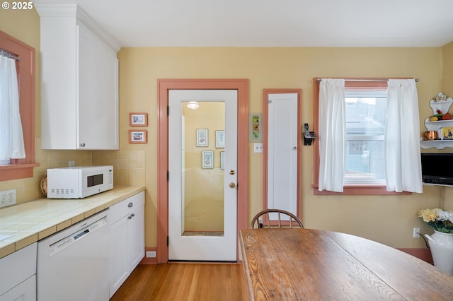 kitchen with decorative backsplash, white cabinets, white appliances, and light wood-style flooring