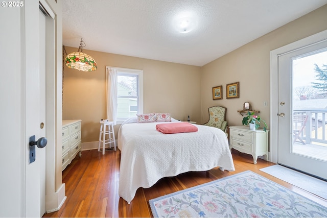 bedroom with access to exterior, a textured ceiling, baseboards, and light wood-style floors