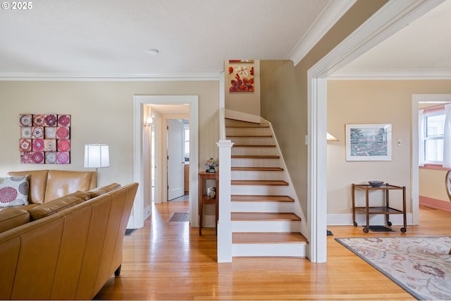 stairs featuring wood finished floors, baseboards, and ornamental molding