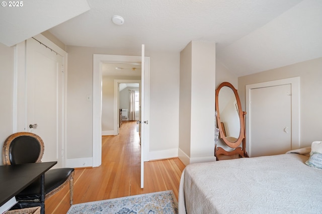 bedroom with lofted ceiling, light wood-type flooring, and baseboards