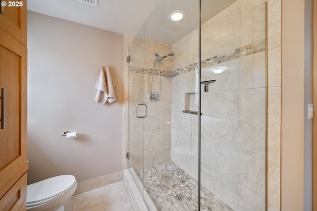 bathroom featuring a shower stall, toilet, and tile patterned floors