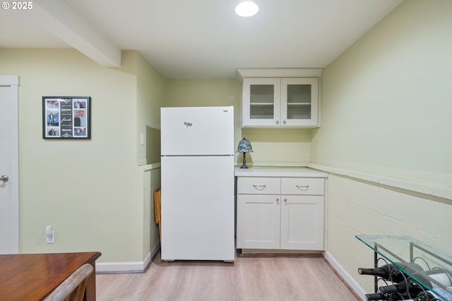 kitchen featuring white cabinetry, light wood-style flooring, glass insert cabinets, and freestanding refrigerator