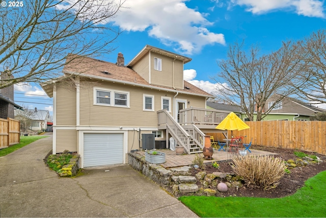 back of property with a patio, fence, concrete driveway, an attached garage, and stairs