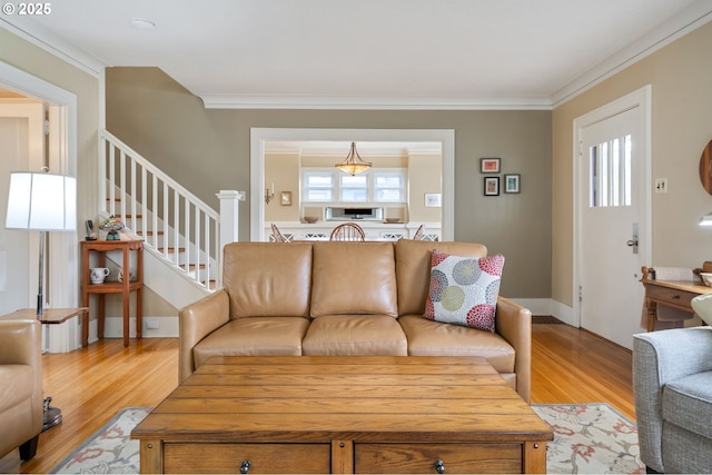 living area with stairs, light wood-style floors, baseboards, and ornamental molding