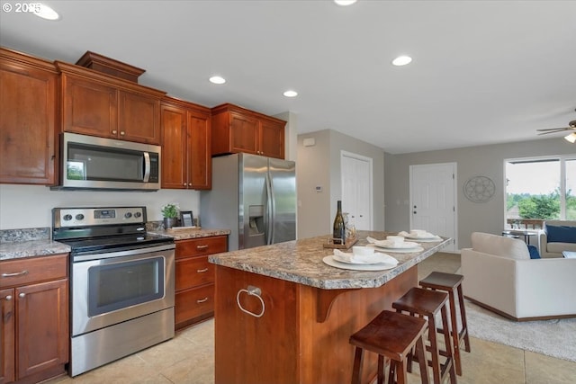 21795 SE Grand Island Loop, Dayton, OR 97114 - kitchen with stainless steel appliances, open floor plan, light tile patterned floors, a kitchen bar, and ceiling fan