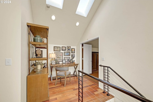 corridor with wood-type flooring, a skylight, and high vaulted ceiling