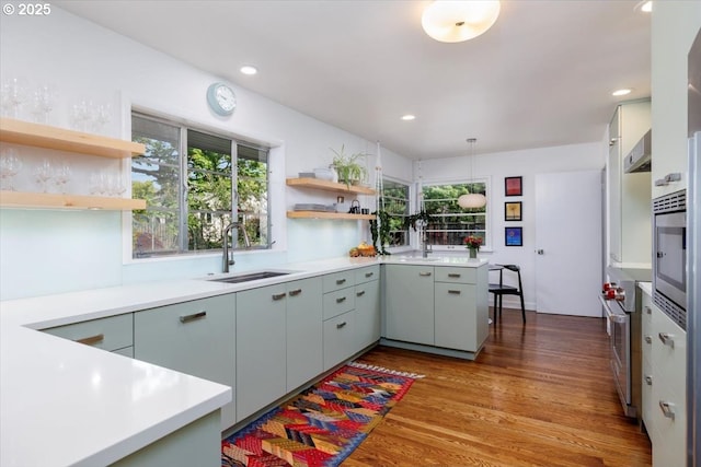 kitchen with light countertops, open shelves, a sink, and wood finished floors