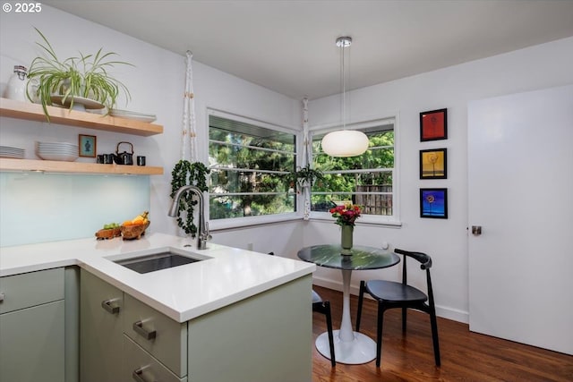 kitchen featuring gray cabinetry, light countertops, a sink, dark wood finished floors, and hanging light fixtures