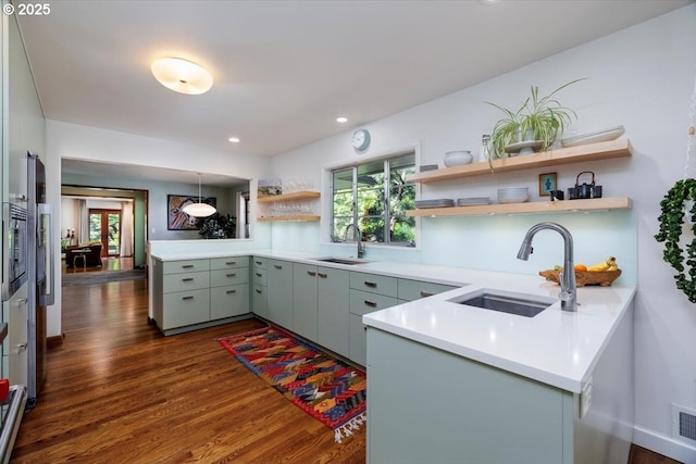 kitchen with a sink, open shelves, a peninsula, and dark wood-type flooring