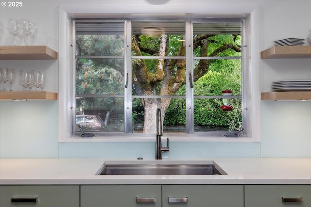 kitchen with light countertops, open shelves, and a sink