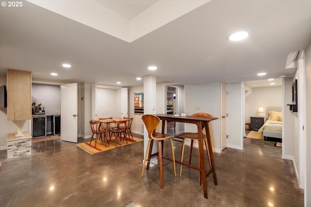 dining space with baseboards, a dry bar, finished concrete flooring, and wine cooler