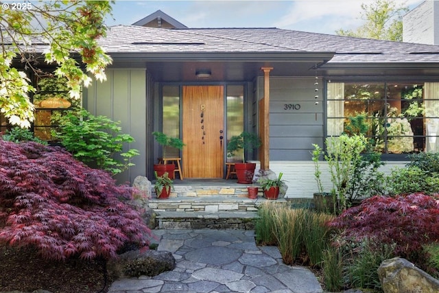 property entrance featuring board and batten siding, roof with shingles, and a chimney