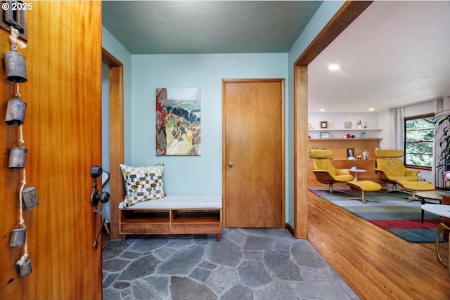 foyer with stone finish floor, recessed lighting, and a textured ceiling